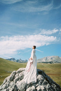 Full length of woman standing on rock against landscape