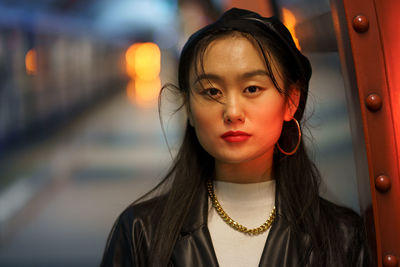 Urban fashion portrait of chinese woman wear leather beret and jacket, earrings at subway platform