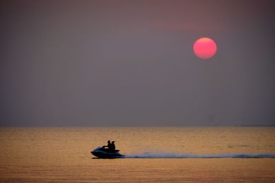 Silhouette boat in sea against clear sky during sunset