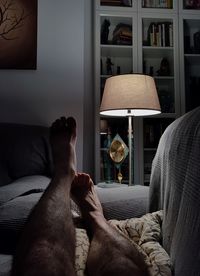 Low section of man lying on sofa at home