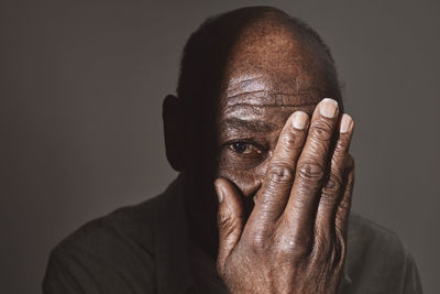 Elderly man covering eye with hand at studio
