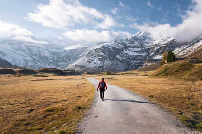 Woman walking on footpath amidst fall colored highland and snow capped mountains in gastein, austria