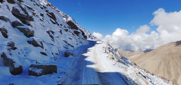 Panoramic view of snow covered mountains against blue sky