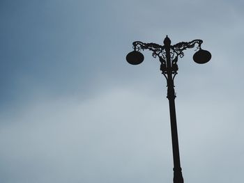 Low angle view of silhouette street light against blue sky