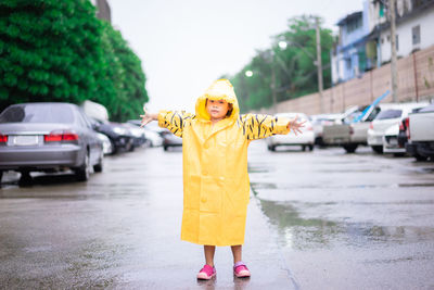 Portrait of woman with umbrella standing on street during rainy season