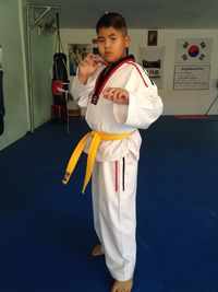 Portrait of boy in karate uniform standing in gym