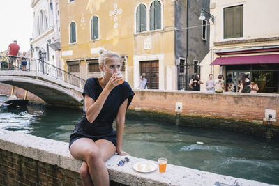 Full length of man sitting at canal