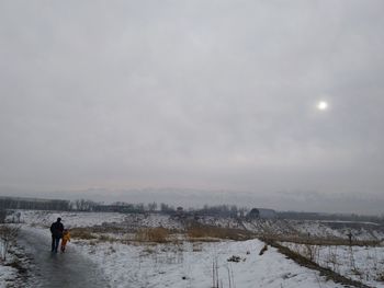 Rear view of people standing on snow covered landscape