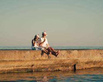 Dad and daughter in santa claus hats eat ice cream on the pier