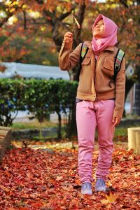 Full length of woman standing in park during autumn