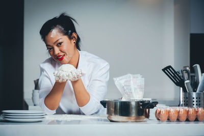 Portrait of smiling woman holding ice cream on table