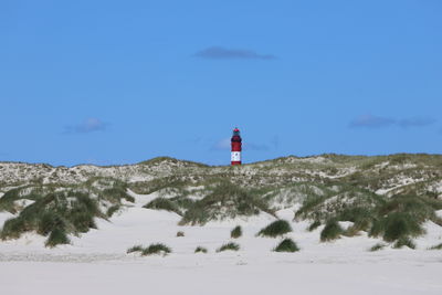 Lighthouse on sand covered land against sky