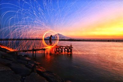 Scenic view of illuminated sea against sky at night