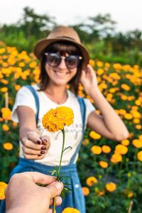 Cropped hand of friend giving flower to woman