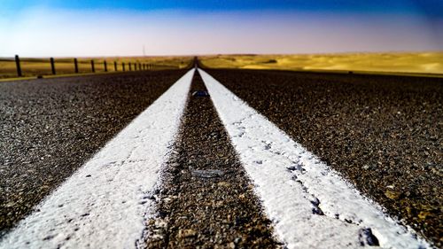 Surface level of road amidst field against sky