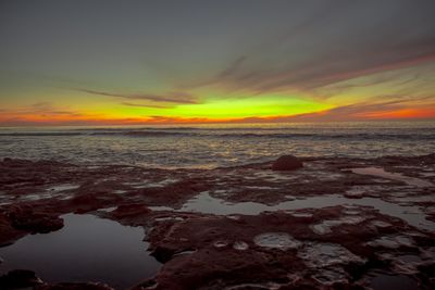 Scenic view of sea against dramatic sky during sunset