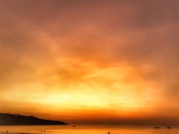 Scenic view of sea against dramatic sky during sunset