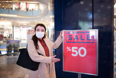 Portrait of woman standing by information sign