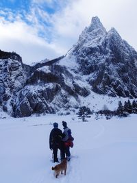 Rear view of people walking on snowcapped mountain against sky