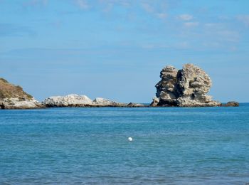 Rock formation in sea against sky