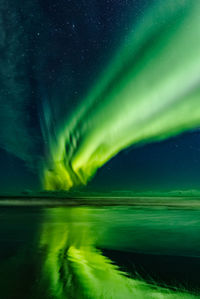 Scenic view of aurora borealis reflecting on lake against sky at night