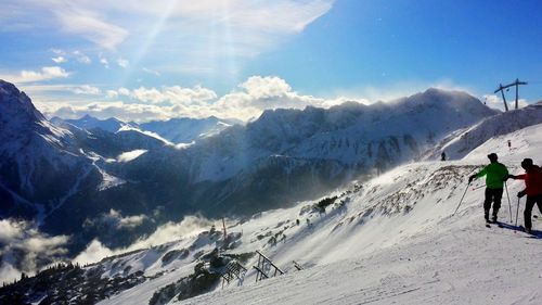 People skiing on snowcapped mountain against sky