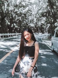 Portrait of a smiling young woman standing against trees