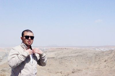 Man wearing sunglasses at desert against clear sky