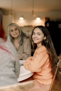 Portrait of smiling girl sitting with family at dining table