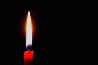 Close-up of lit candle in darkroom