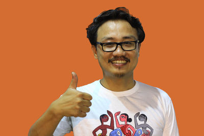 Portrait of young man with eyeglasses against orange background