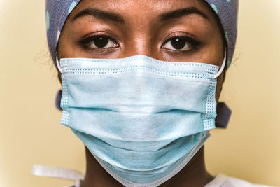 Close-up portrait of doctor wearing mask against colored background