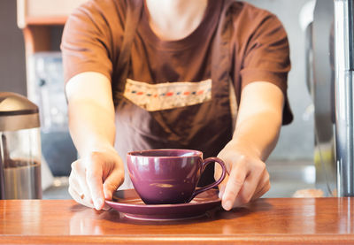 Midsection of woman holding coffee at table