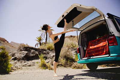 Low section of woman standing by car against sky