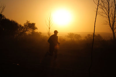 Silhouette man standing against sky during sunset