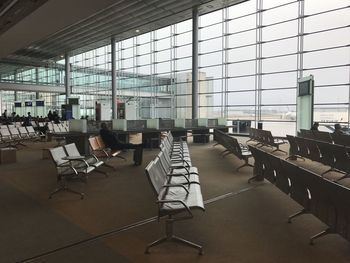 Empty chairs and tables in airport against sky