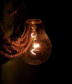 Close-up of illuminated light bulb against black background