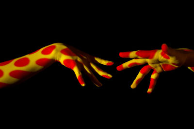Close-up of two hands over black background