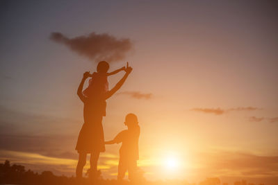 Silhouette friends standing against sky during sunset