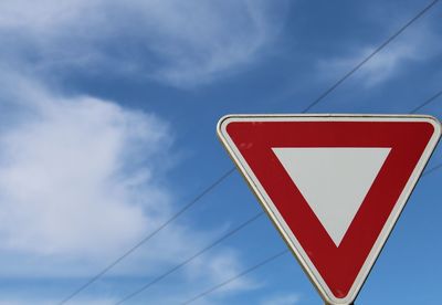 Low angle view of yield sign against sky