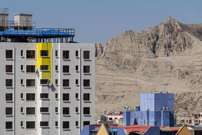 Buildings by sea against clear blue sky