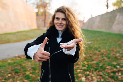 Portrait of smiling young woman holding broken cigarette while showing thumbs up