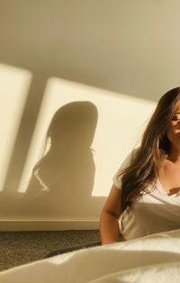 Portrait of woman sitting on wall at home