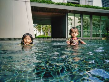 Portrait of siblings swimming in pool