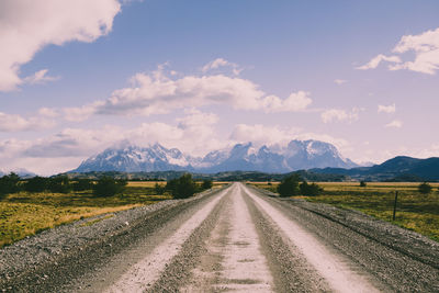 Empty road along landscape and mountains against sky