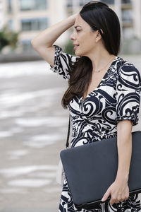Young woman looking away while standing outdoors