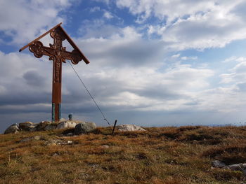 Traditional cross on field against sky