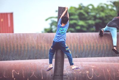 Rear view of boy with arms raised against sky