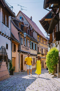 Rear view of people walking amidst buildings in city