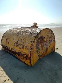 Rusty metal on beach against sky